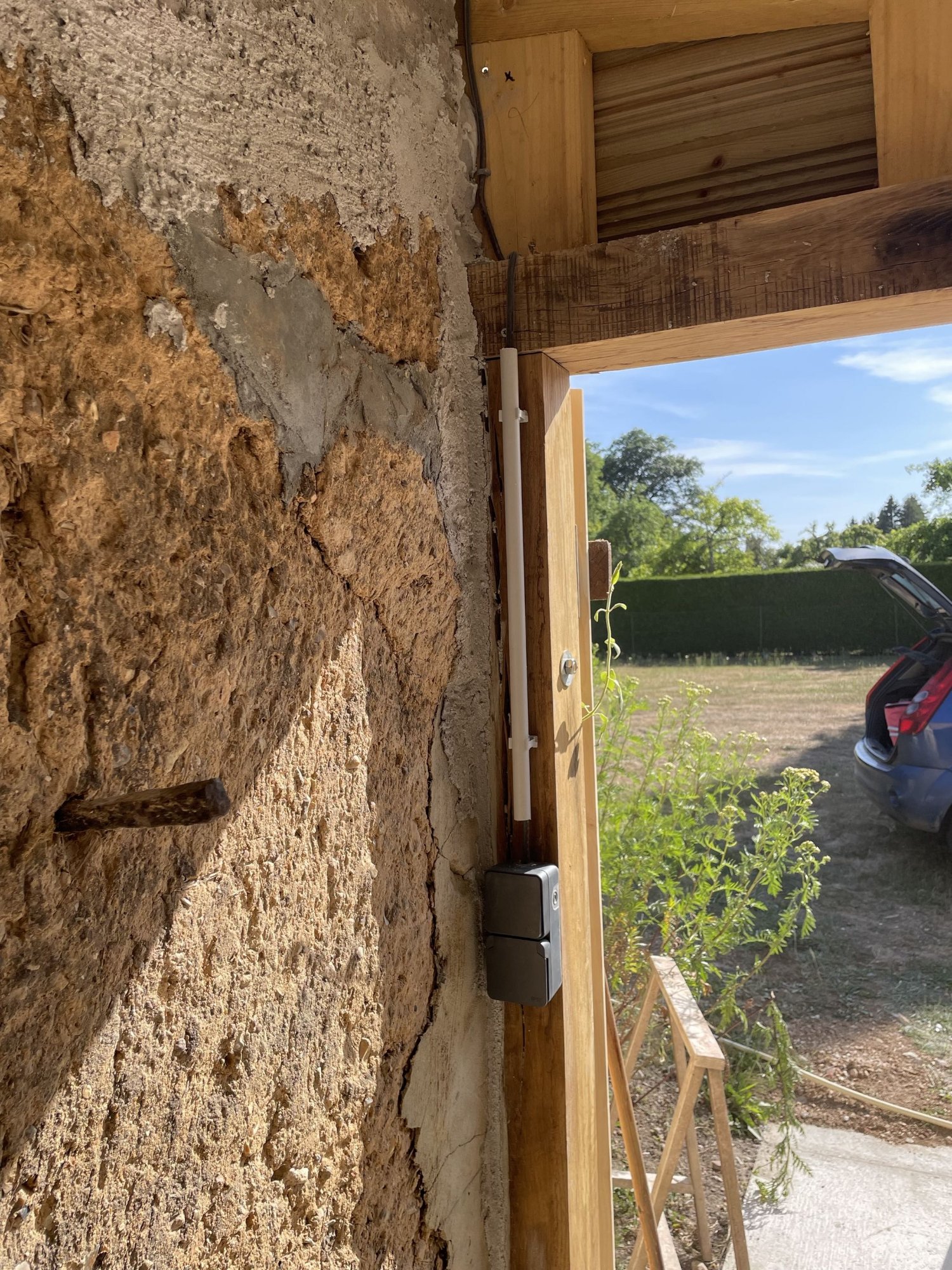 Tableau électrique secondaire et passage de câbles sous goulotte sur mur en parpaings – vue d'ensemble du cheminement