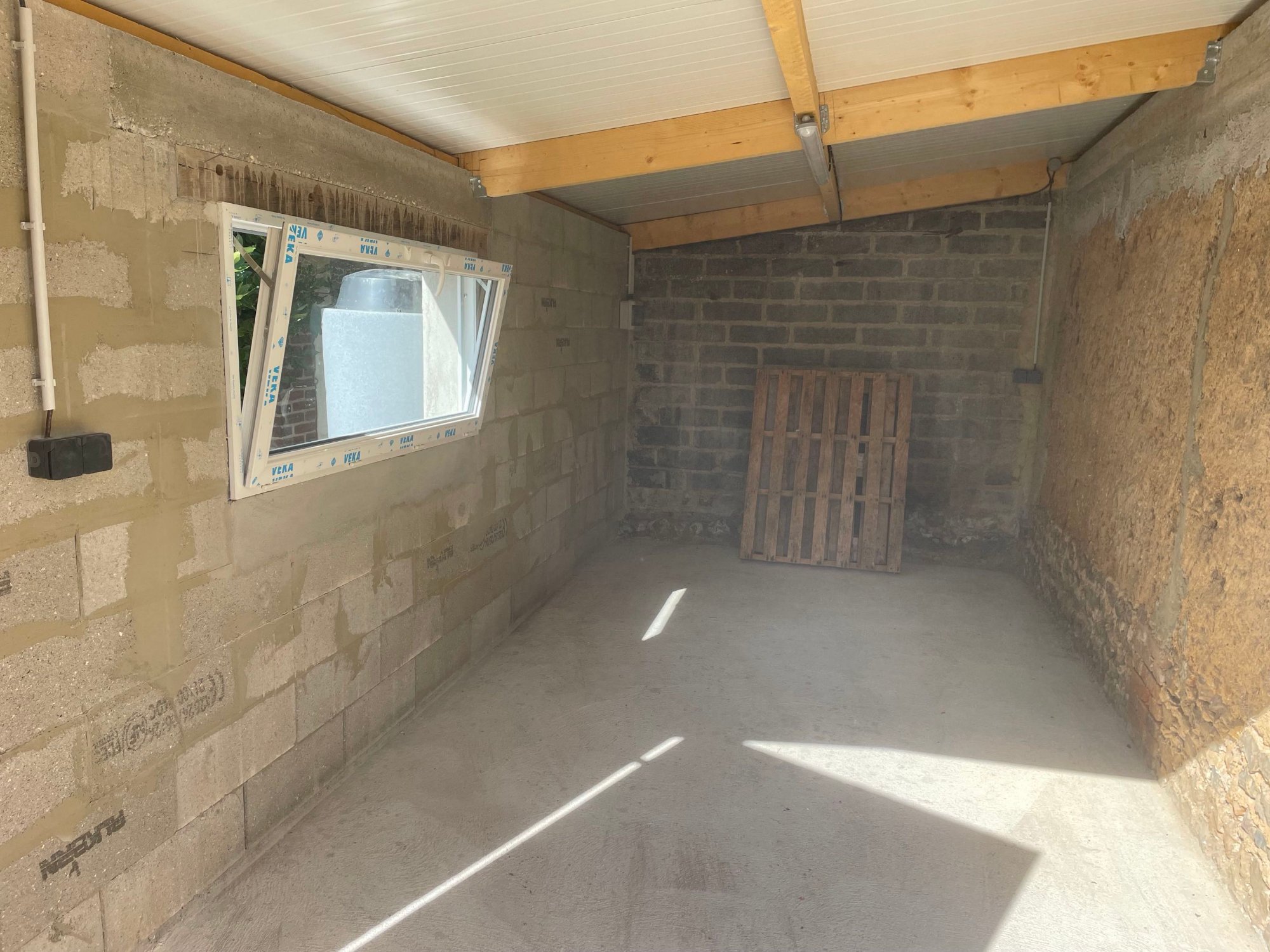 Vue d'ensemble intérieure du garage après installation électrique complète – éclairage, prises et câblage apparent soigné